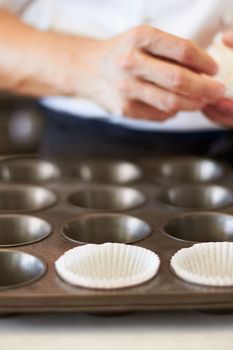 Ready to put the delicious cupcake batter in. A close up of a cupcake tray with some cupcake holders in the tray.
