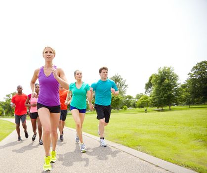 Promoting a healthy habit. Front view of a group of male and female athletes running on an outdoor track.