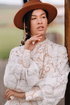 Beautiful girl in vintage lace dress and hat at the ranch