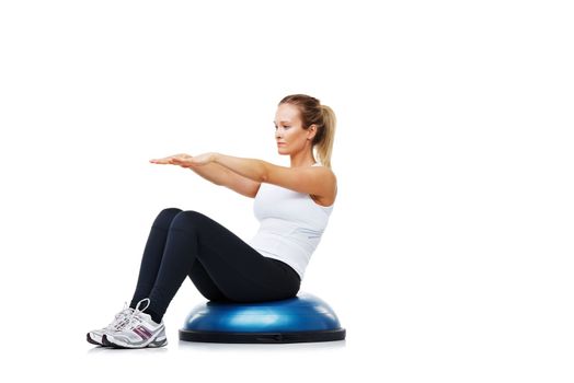Shes in peak physical condition. A young woman sitting on a bosu-ball while exercising.