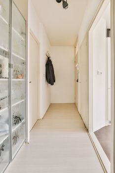 a long white hallway with glass doors and a wardrobe