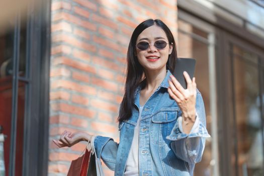 Asian fashionable woman walking at shopping mall with shopping bags while flash sale promotion