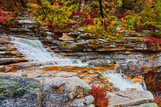 Beautiful layers of rocks in river with cascading waterfalls and fall trees