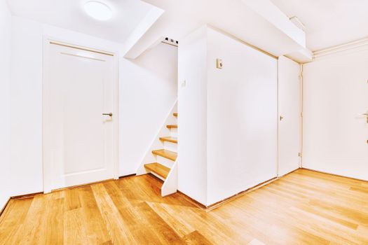 a room with white walls and stairs and a door