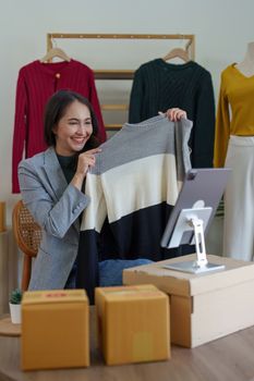 Asian Woman fashion designer cloth tailor creative working for new collection. Happy online store owner preparing an order for shipping