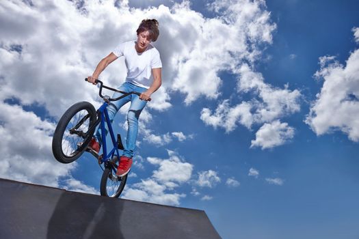 Practicing for the x games. a teenage boy riding a bmx at a skatepark.