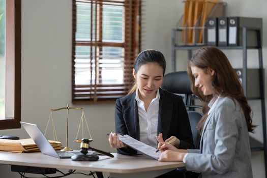 Female lawyer discuss to a legal document explaining the terms of a consultation with a businesswoman. before signing a contract with a law firm.