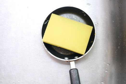 sponge on a cooking pan on a sink 