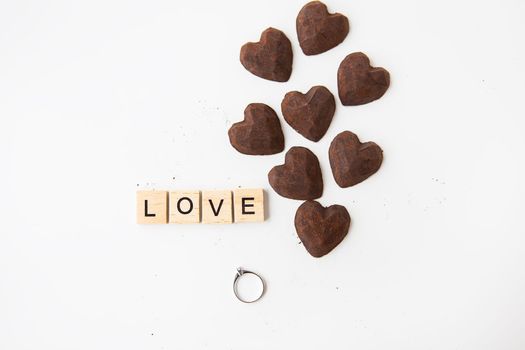 The inscription in wooden letters love, small truffle candies in the form of a heart. Ring with a diamond - a proposal of a hand and a heart.