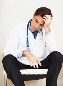 Overworked doctor with hand on head , looking stressed out. Portrait of an overworked doctor with hand on head , looking totally stressed out.