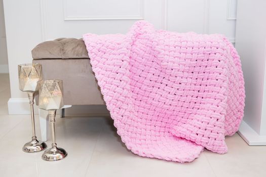 Background texture of plush fabric in pink color, background pattern of soft woolen material that lies on a small sofa along with candlesticks, cozy concept.