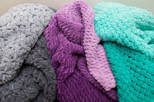 Beautiful plush multi-colored blankets of different colors lie together. Close-up.