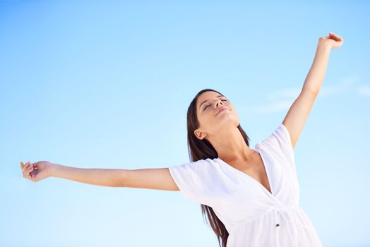 Utterly free...A carefree young woman standing with her arms outstretched against a blue sky.