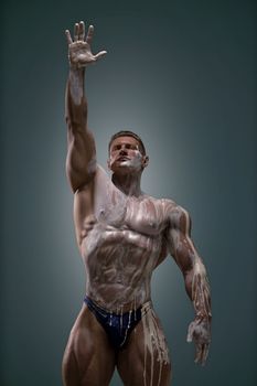 Athletic man posing at the studio with his arm up