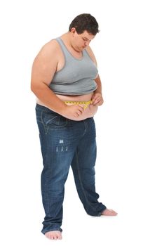 Watching his weight. An obese young man measuring his waist with a measuring tape against a white background.