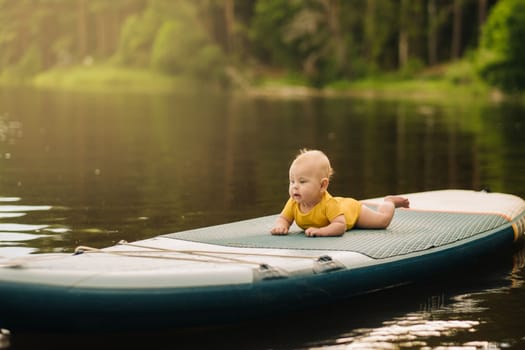 The child lies floating on the water on a large sup board. Water sports