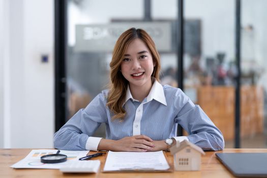 Young asian businesswoman real estate agent looking on camera at her office.