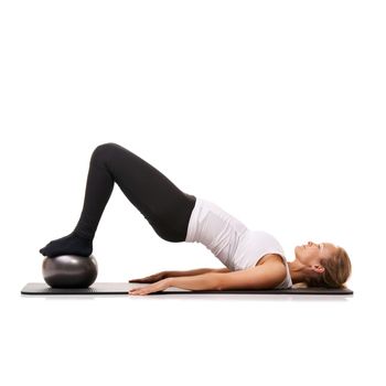 Shes making great progress. A young woman using an exercise ball to raise her back into the air - isolated.