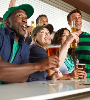 What a game. A group of friends cheering on their favourite sports team at the bar.