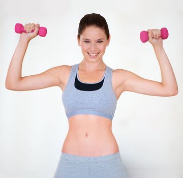 Firming up. Portrait of an attractive young woman in sporty clothing training with dumbbells.