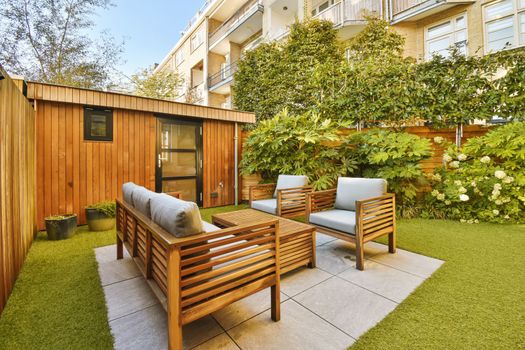 a backyard patio with wooden furniture and a lawn
