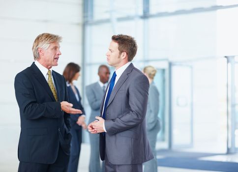 Executives discussing with business people. Portrait of male executives discussing with business people in background.