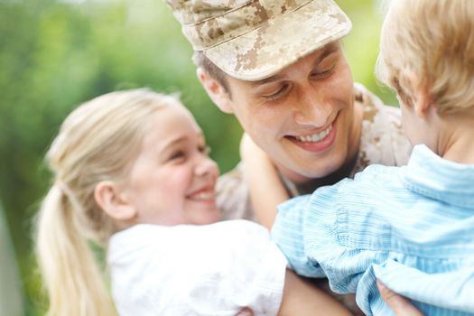 Hes their hero. A returning soldier being welcomed by his two young children.