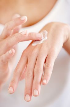 Moisturizing her skin. Cropped image of a young woman applying cream to the back of her hand.