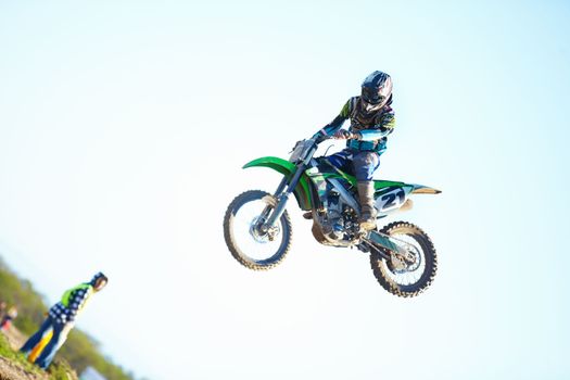 Smooth landing. A motocross racer in mid-air with a spectator looking on in the background.