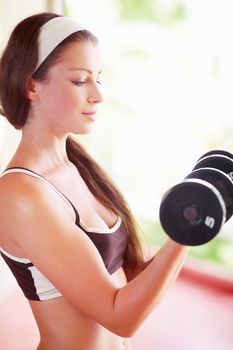 A fit young woman doing bicep curls with a pair of dumbbells