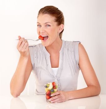 A healthy diet improves her day. A lovely young woman eating a healthy fruit salad.