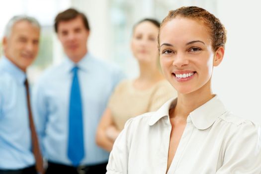 Successful female executive with her team in background. Successful young female executive smiling with her staff in background.