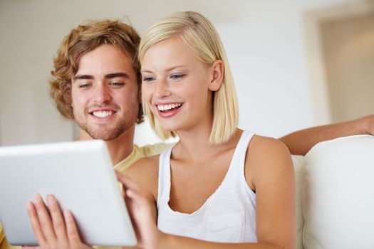 Functionality for everyone. A happy young couple using a tablet together in their lounge.