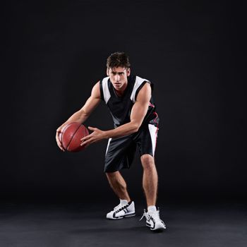 Feeling intimidated by my awesomeness yet. Full length portrait of a male basketball player in action against a black background.