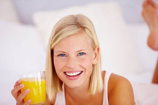 Freshly-squeezed goodness. Lovely young woman lying down with a glass of orange juice and a tray of breakfast.