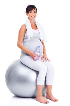 Keeping in shape, right down to her final trimester. A pregnant mother smiling with a pilates ball while isolated on white.