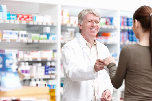 Male pharmacist giving package to customer. Portrait of male pharmacist delivering the package to customer at drugstore.