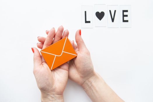 A love letter holding a small wooden orange envelope. Love lettering.