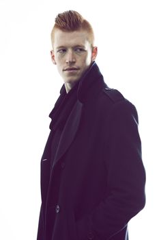 Hes got his own sense of style. A redheaded man wearing a black jacket standing in a studio and looking at the camera.