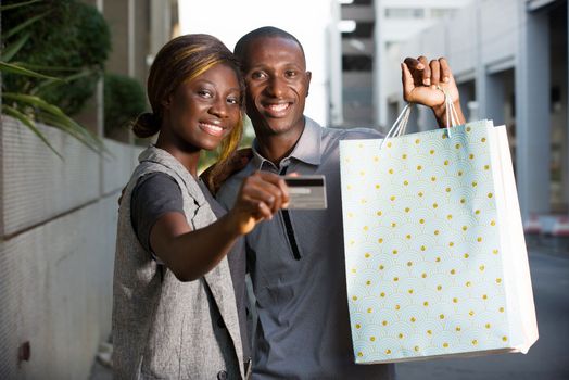 Couple holds shopping bags with a credit card outside