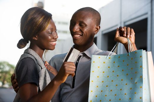 Couple holds shopping bags with a credit card outside