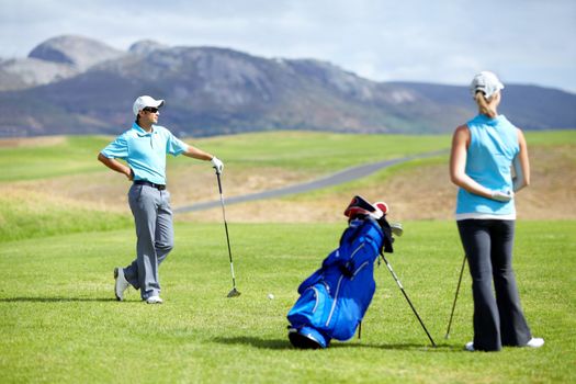 A relaxing round of golf. Image of a young couple waiting patiently to commence their round of golf.