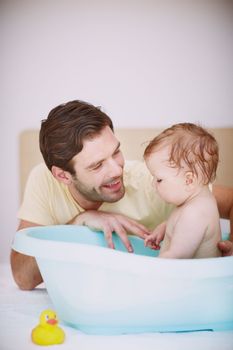 Hes commited to caring for her. A young father bonding with his baby daughter at bathtime.