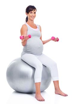 Keeping in shape, right down to her final trimester. A pregnant mother smiling with a pilates ball while isolated on white.