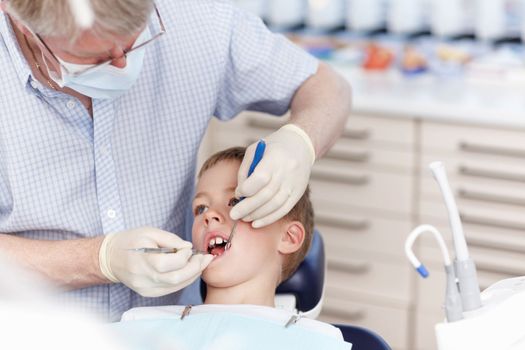 Dentist working on childs teeth. Portrait of mature dentist working on childs teeth in clinic