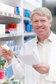 Pharmacist with medicine and prescription. Portrait of happy pharmacist with medicine and prescription at pharmacy.