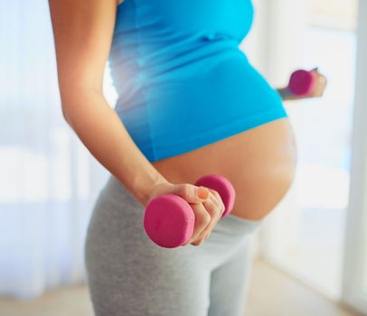 Fit weights on no one. a pregnant woman working out with weights at home.