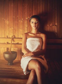 This sauna feels amazing. Cropped portrait of a young woman relaxing in the sauna at a spa.