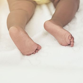 These feet will leave big foot prints one day. a baby girl asleep on a bed at home.