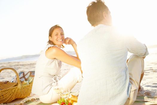 Life has never been better. A loving couple watching the sunset while enjoying a picnic together on the beach.